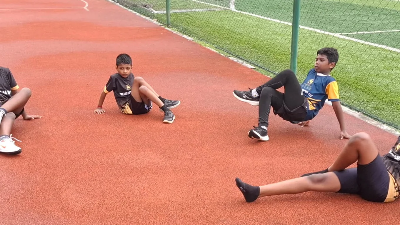 Athletes resting and stretching trackside after a session