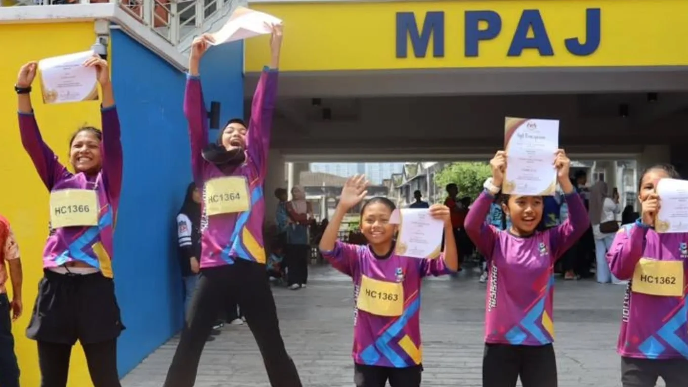 Athletes celebrating with their certificates held overhead, one of them airborne